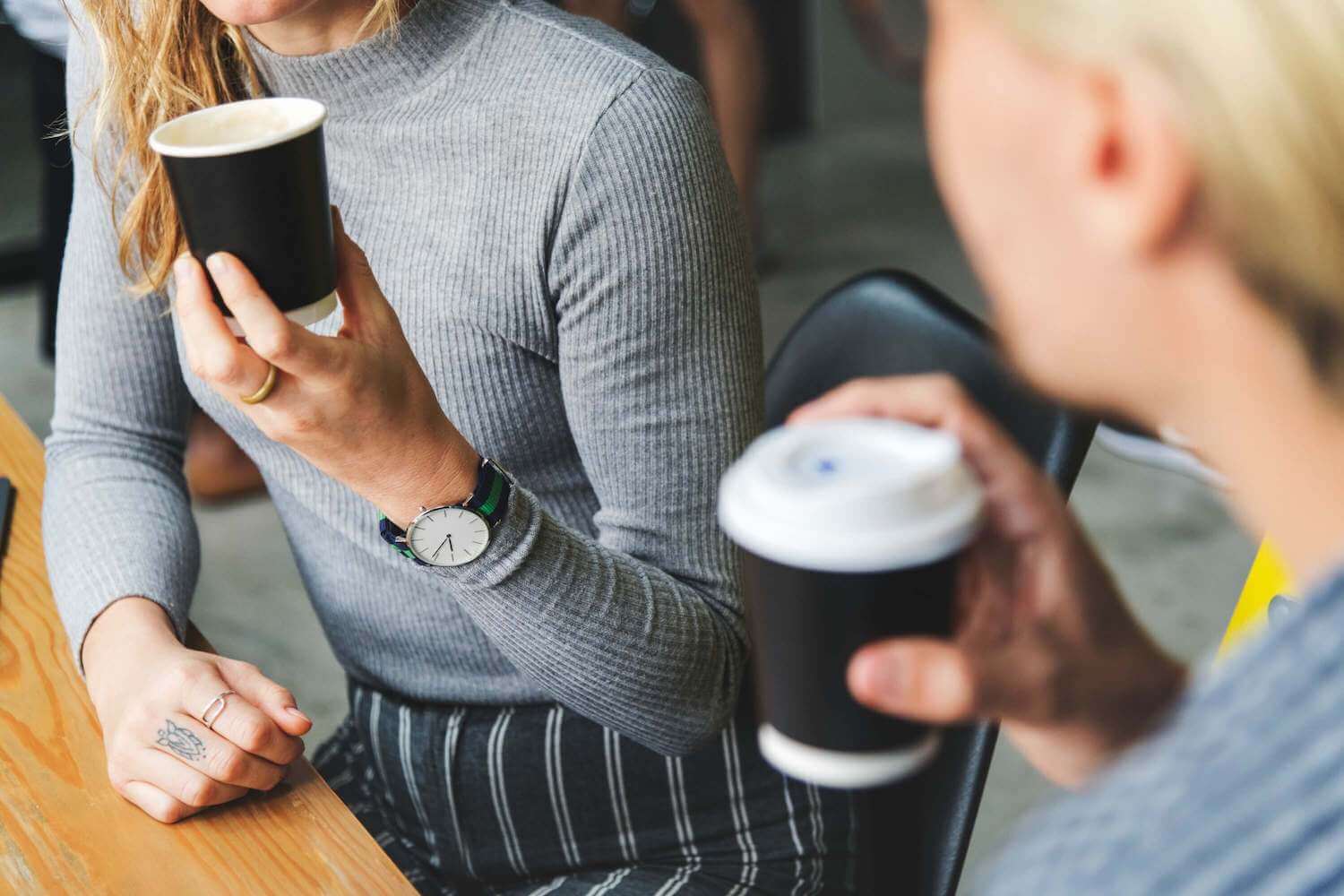 two girls drinking coffee together at table