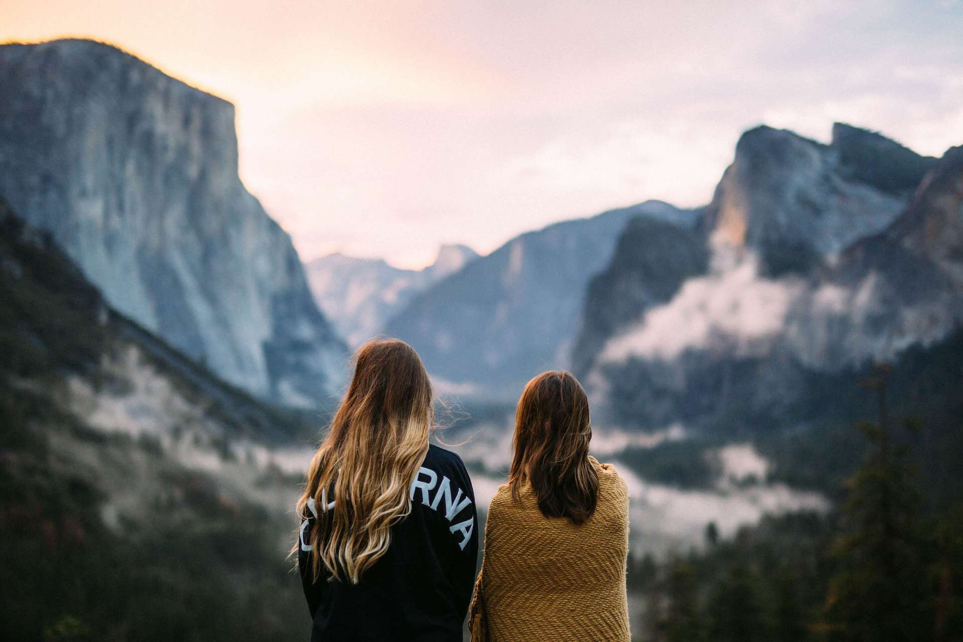 two girls standing looking at view of mountains