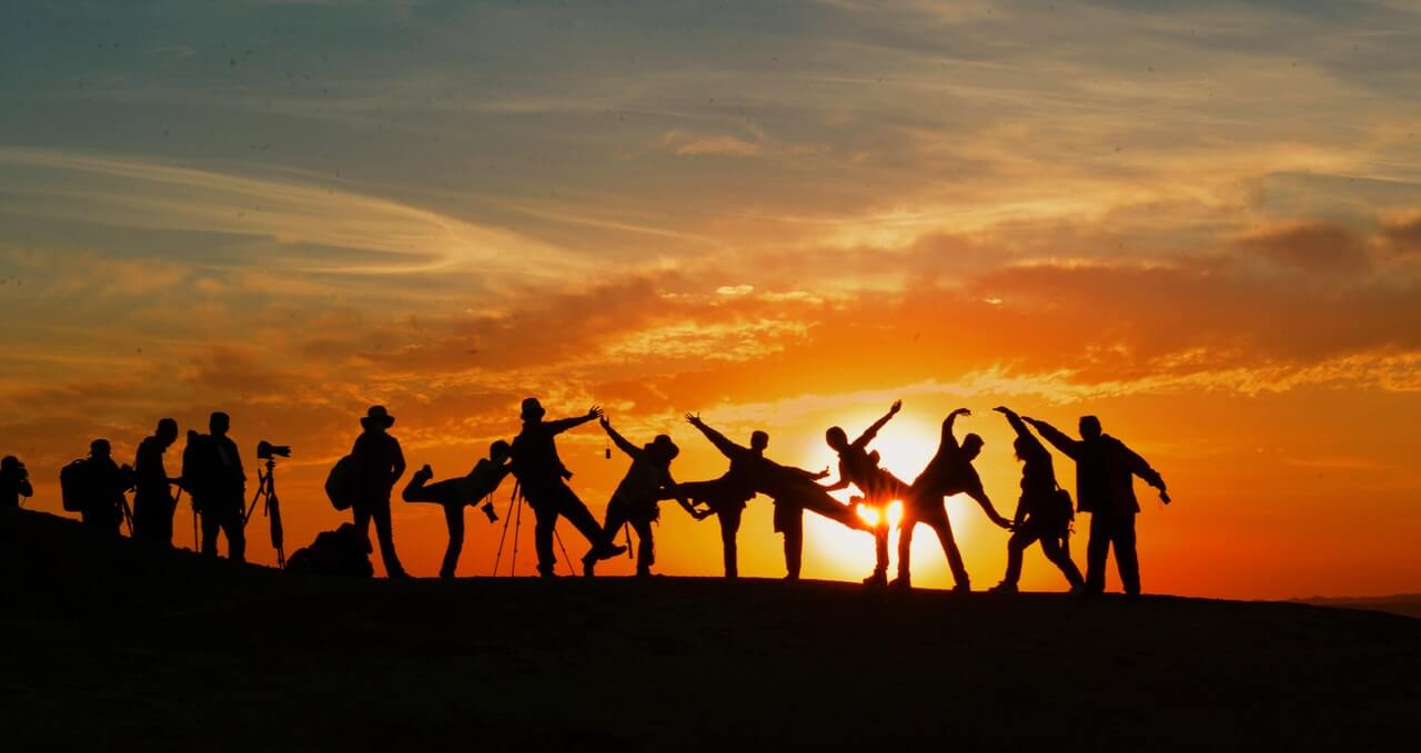 group of people making shapes with their body at sunset