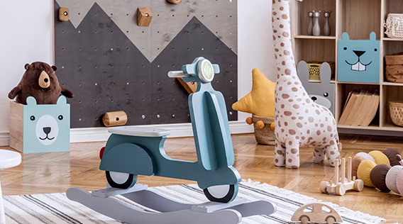 Bunt eingerichtetes Kinderzimmer mit Stofftieren, Kisten im Tierdesign und Schaukelspielzeug