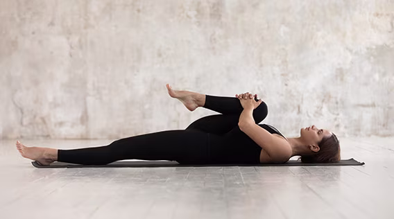 Frau die Dehnübungen auf der Yogamatte macht