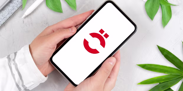 Hände die ein refurbished Smartphone halten, umgeben von Pflanzen auf hellem Hintergrund