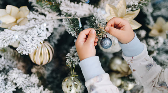 Kind beim Christbaum schmücken