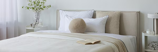 Ein modernes Schlafzimmer mit einem frisch gemachten Bett in Erdtönen | shöpping.at