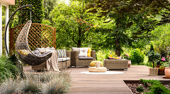 Möbel auf Boho-Terrasse mit Garten im Hintergrund