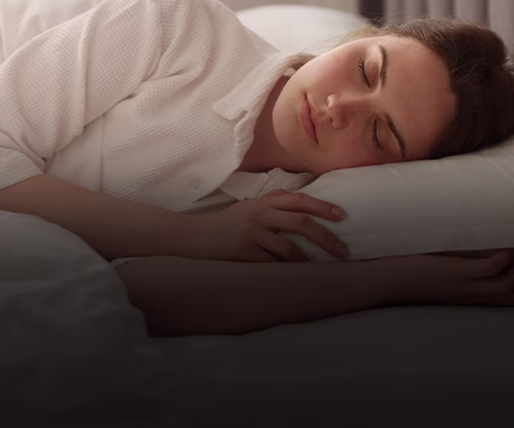 Frau die mit geschlossenen Augen und entspannt seitlich im Bett liegt | shöpping.at