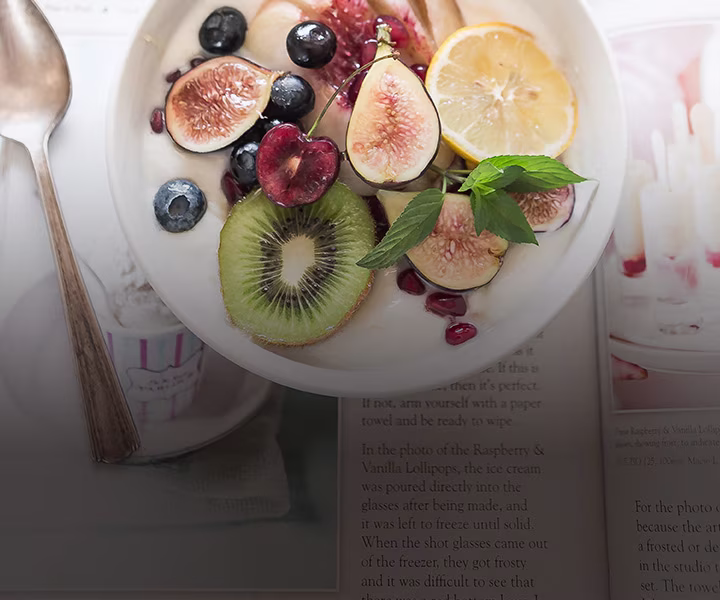 Bowl mit Joghurt und Früchten mit Löffel auf Magazin