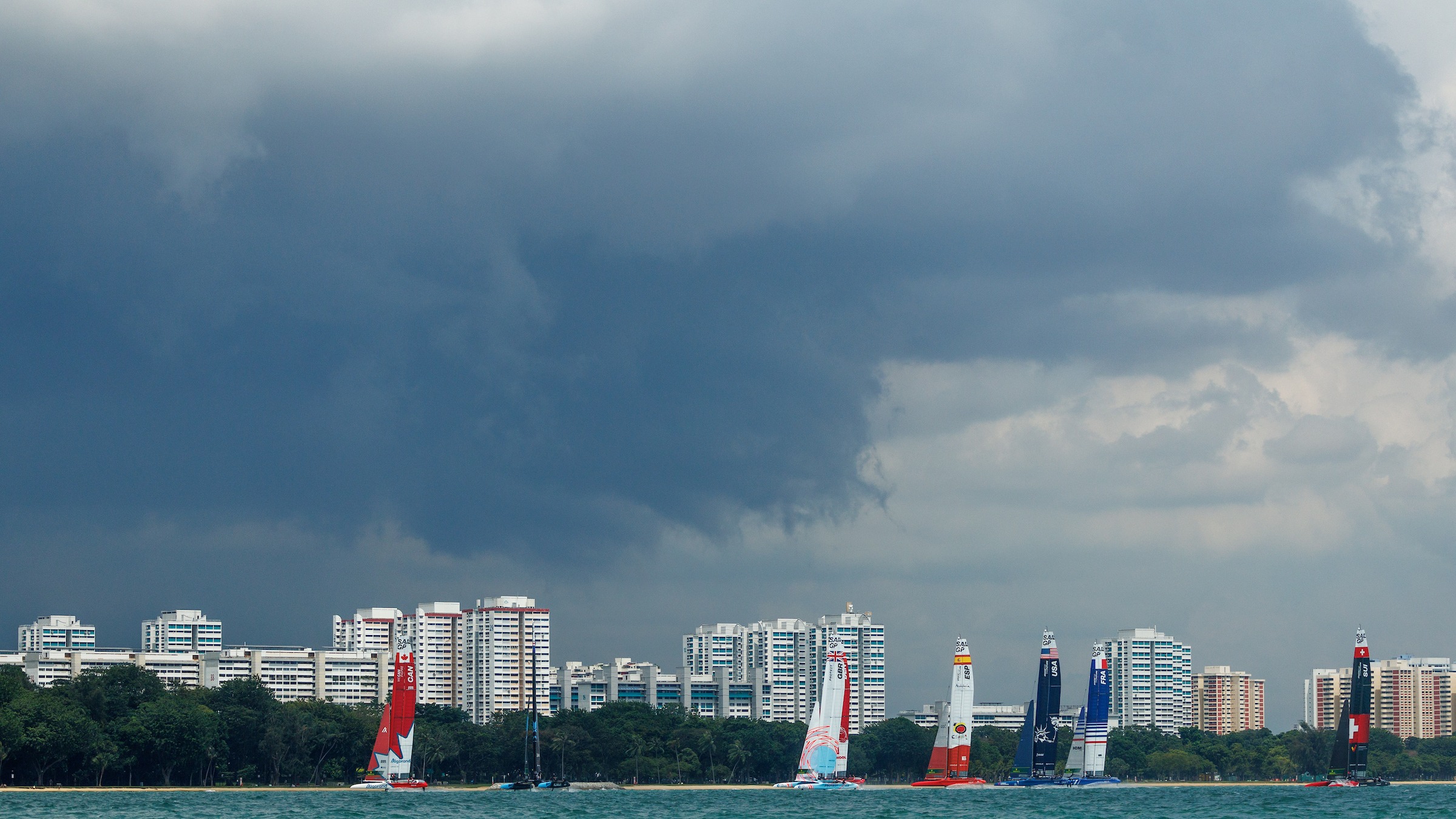 Season 3 // Singapore Sail Grand Prix // Fleet with city skyline under stormy clouds