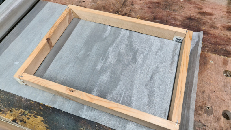 Stainless steel filter mesh is relatively inexpensive and rugged enough to stand up to bombardment from lasers and squeegees. Staple the mesh onto the frame as though you’re stretching a canvas