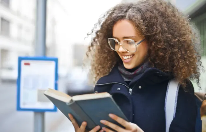 Jeune femme souriante lisant le livre