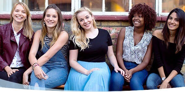 Cinq jeunes filles souriantes assises sur un banc
