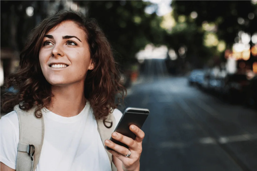 Jeune fille souriante avec un smartphone à la main