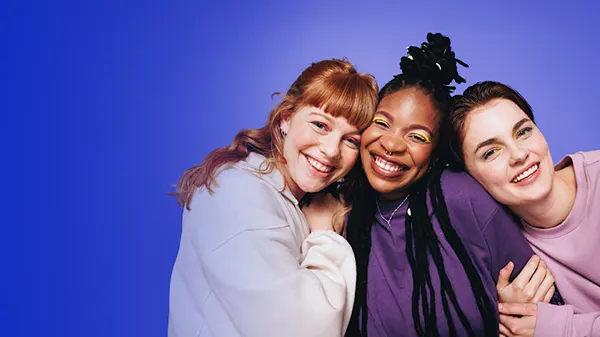 Three young women hugging and smiling next to the text period hub answer for all your questions on periods