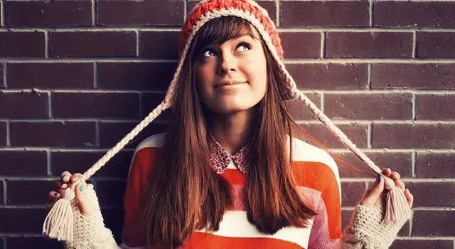 Jeune fille dans un chapeau d'hiver debout contre le mur
