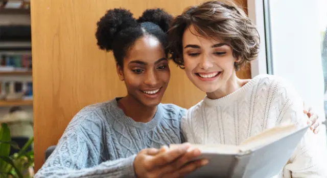 Deux jeunes filles souriantes lisant un livre