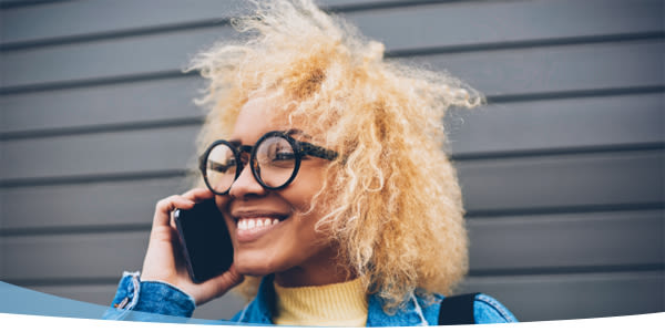 Jeune femme souriante avec des lunettes qui parle au téléphone