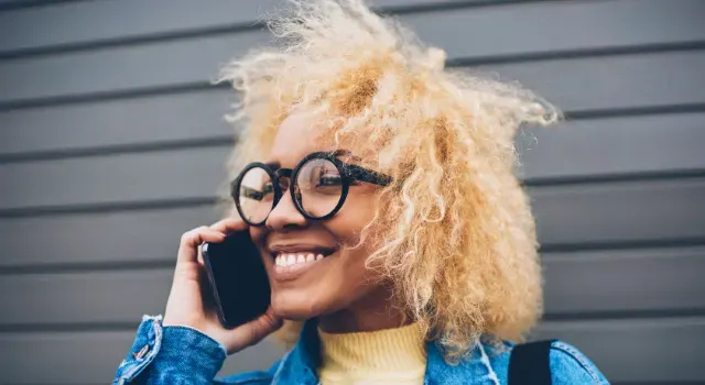 Jeune femme souriante avec des lunettes qui parle au téléphone