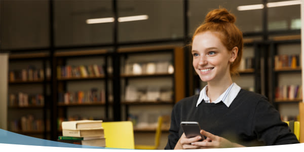 Jeune fille souriante assise dans la bibliothèque