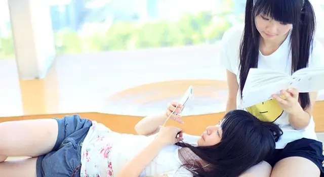 Deux jeunes filles avec un smartphone à la main assises sur un banc 