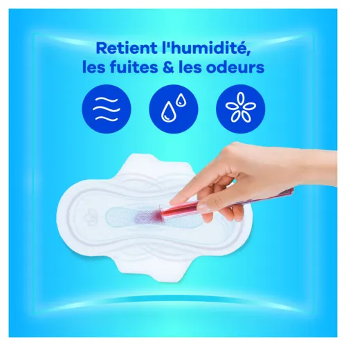 Main versant un liquide rouge sur une serviette Ultra retenant l'humidité, les fuites et les odeurs.