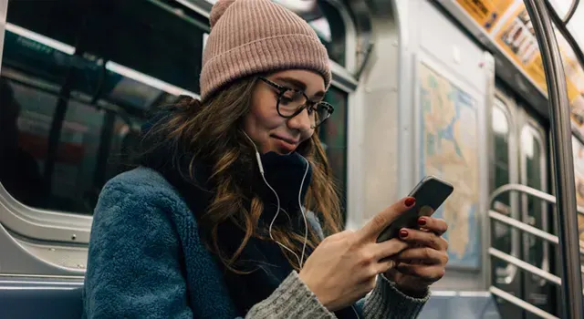 Jeune fille dans le métro avec un smartphone à la main