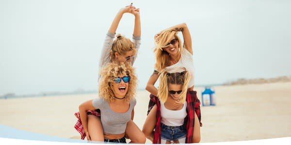 Quatre filles qui rient marchant sur la plage