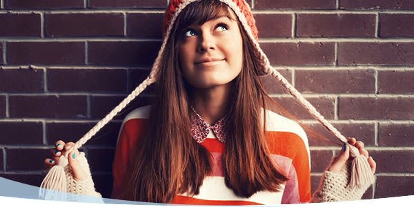 Jeune fille dans un chapeau d'hiver debout contre le mur