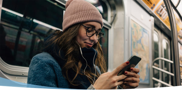 Jeune fille dans le métro avec un smartphone à la main