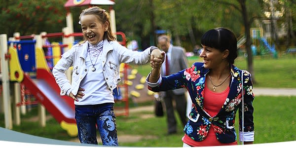 Maman et petite fille marchant main dans la main sur le terrain de jeu à l'extérieur