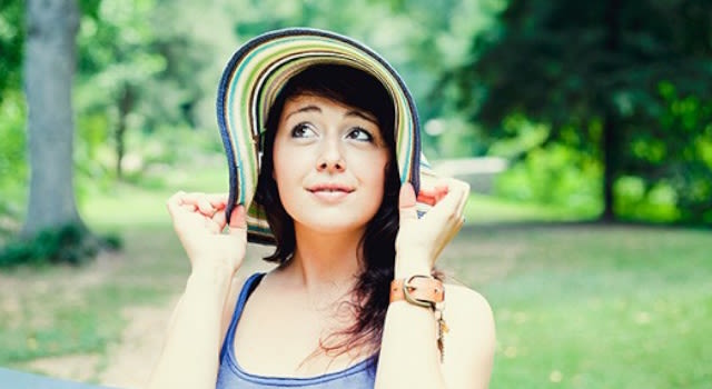 Jeune fille au chapeau debout dans le parc