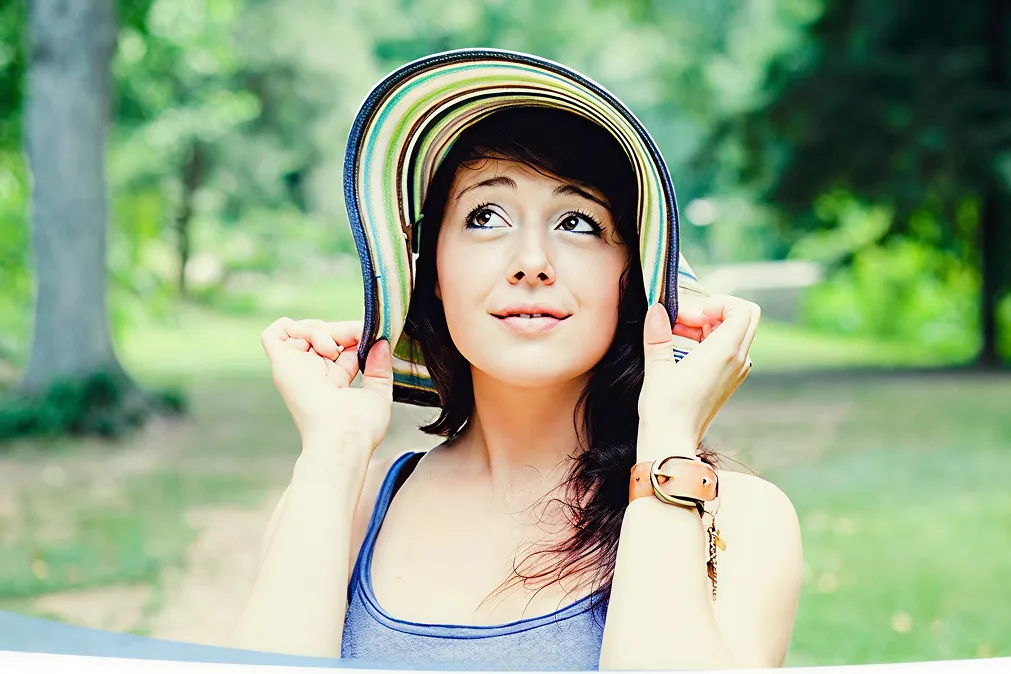 Jeune femme couvrant son visage avec chapeau