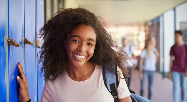 Fille souriante avec sac à dos à l'école