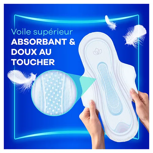 Mains tenant une serviette menstruelle avec ailettes Always Ultra avec une loupe montrant le voile supérieur absorbant et doux au toucher
