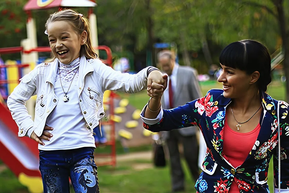 Maman et petite fille marchant main dans la main sur le terrain de jeu à l'extérieur