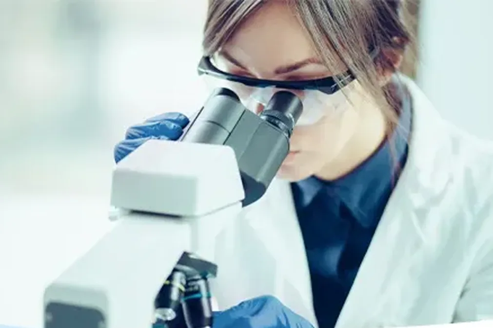 Jeune femme regardant à travers un microscope