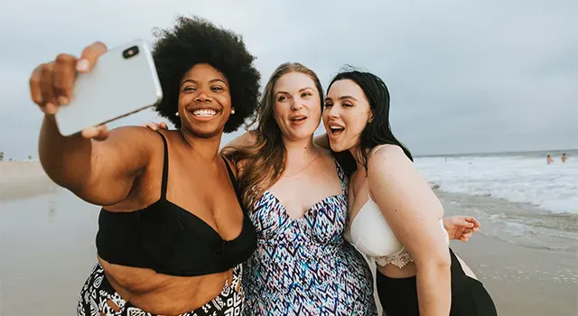 Trois jeunes femmes souriantes prennent un selfie sur la plage