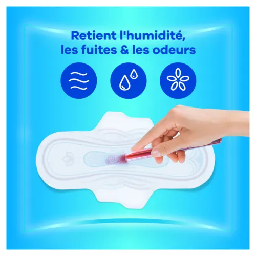 Main versant un liquide rouge sur une serviette Ultra retenant l'humidité, les fuites et les odeurs.