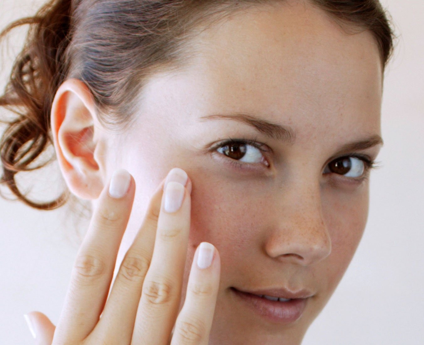 Woman using Johnson's® baby oil for adult skin care on face