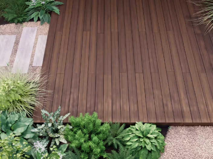 Terrasse en bois foncé entourée de diverses plantes vertes et de gravier, créant un espace extérieur élégant et naturel.