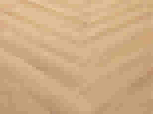 Parquet en bois clair disposé en motif chevron, montrant une surface lisse avec des tons beiges chaleureux.