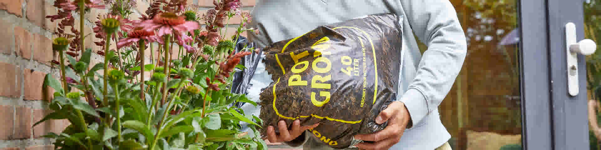 Un homme ajoute du terreau à une jardinière dans le jardin