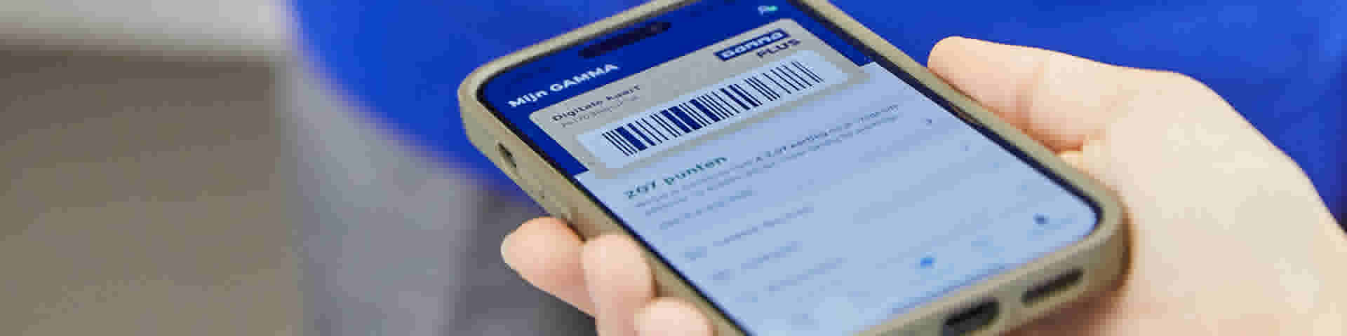 Hand houdt smartphone vast met Gamma app, toont digitale klantenkaart met barcode.