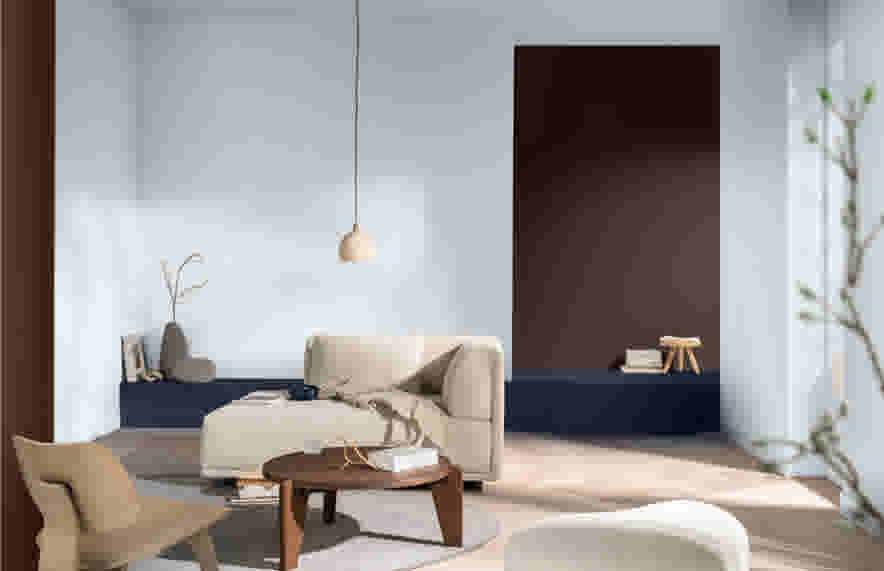 Moderne woonkamer met beige bank, houten salontafel en minimalistische decoratie tegen lichtblauwe muren met donkerbruine accentwand.