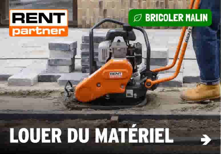 Compacteur de plaque vibrante orange RENT Partner utilisé sur un chantier de pavage avec pavés empilés en arrière-plan.