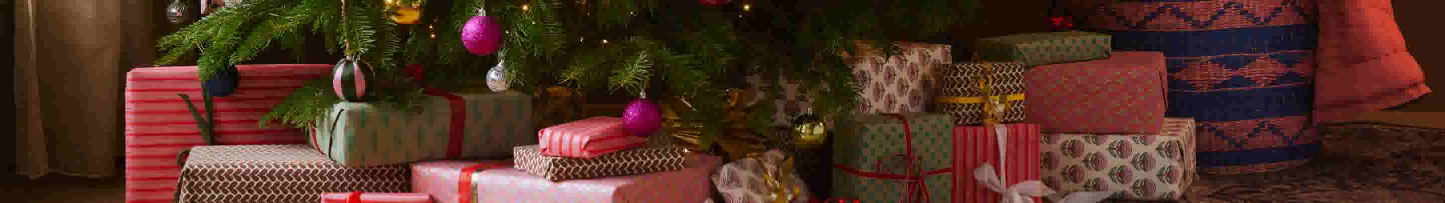 Versierde kerstboom met kleurrijke ballen en lichtjes, omringd door ingepakte cadeaus in verschillende patronen en kleuren.