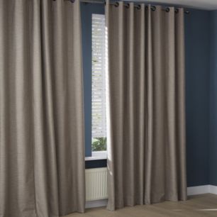 Des rideaux beiges à œillets sont suspendus devant une fenêtre dans une pièce aux murs bleu foncé, avec un radiateur visible en dessous.