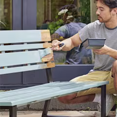 Homme peignant un banc d’extérieur