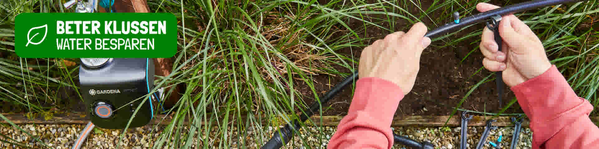 Handen in roze trui installeren een Gardena irrigatiesysteem tussen het gras met tekst "Beter klussen water besparen"