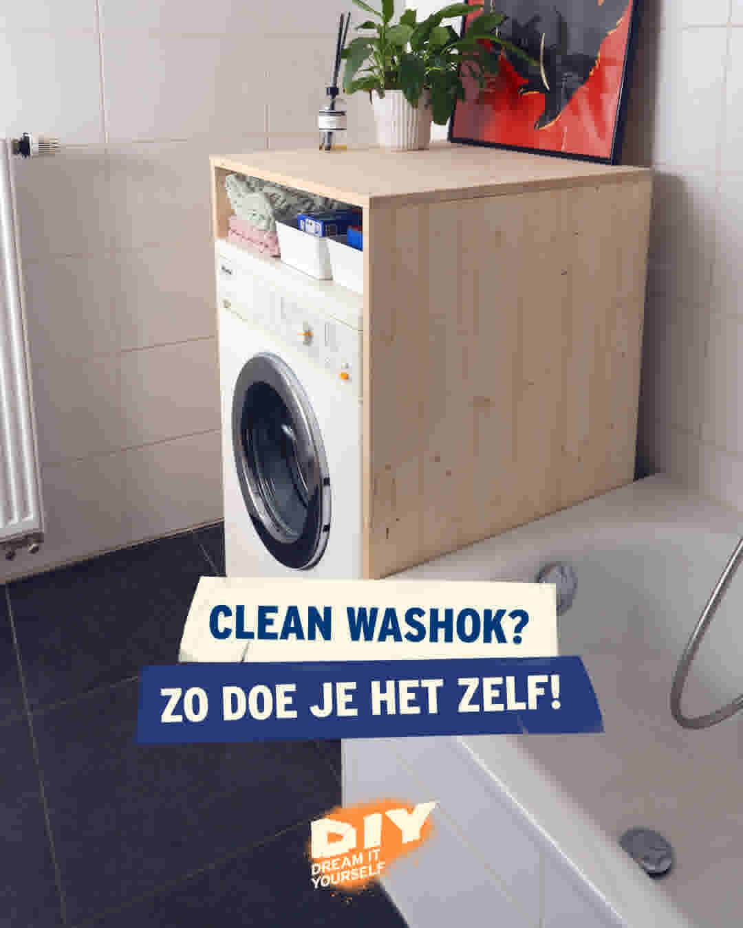 Wasmachine onder houten kast met plant en schilderij in moderne badkamer met witte tegels en donkere vloer.