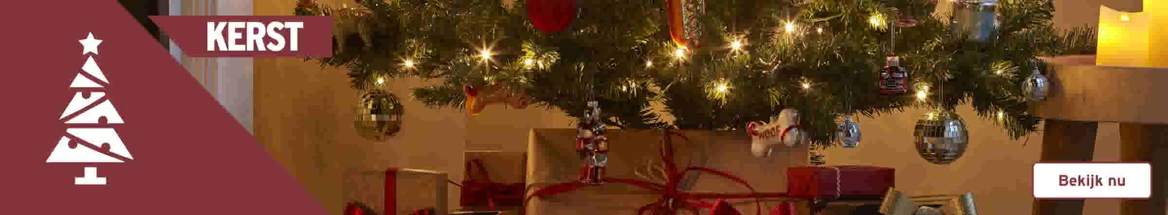 Verlichte kerstboom met gouden en rode cadeaus eronder, kerstballen en een wit boomicoon met tekst 'KERST'